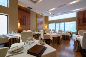 a dining room with white tables and chairs and windows at M.A. Hotel Sevilla Congresos in Seville