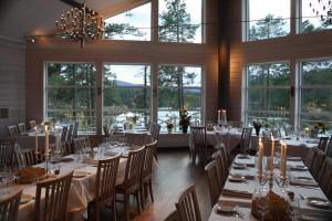 a dining room with tables and chairs and windows at Årrenjarka Mountain Lodge in Kvikkjokks Kapell