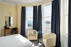 a hotel room with a bed and a table and windows at Four Points Flex by Sheraton Brighton in Brighton & Hove +25 photos