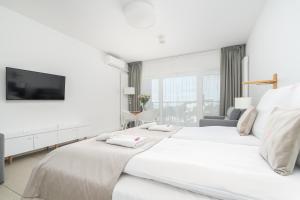 a white bedroom with two beds and a tv at Your Holidays Aquamarina Prima, Parking Gratis in Międzyzdroje