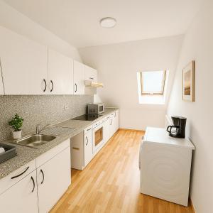 eine Küche mit weißen Schränken und einem Holzboden in der Unterkunft SUNNYHOME Monteurwohnungen und Apartments in Schwandorf in Schwandorf in Bayern