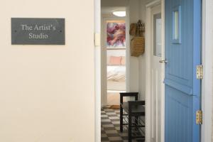 a hallway with a blue door and a room with a bed at The Artists Studio Private Parking Frome in Frome