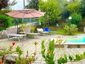 a patio with chairs and an umbrella and a pool at La casa nel verde con piscina in Polverara