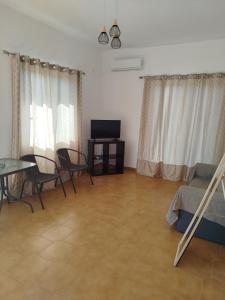 a living room with a table and chairs and a television at Nereids Apartments-Agavi in Petalidi