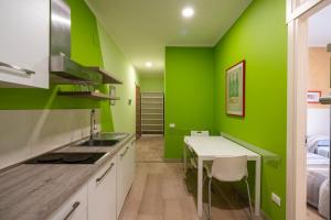 Una cocina con paredes verdes y una mesa y una cama. en Appartamento a due passi dal mare. Civitanova M., en Civitanova Marche 15 fotos más