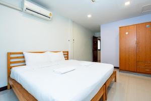 a bedroom with a large white bed and a wooden cabinet at X The Hidden Giant Swing เดอะ ฮิดเด้น เสาชิงช้า in Bangkok