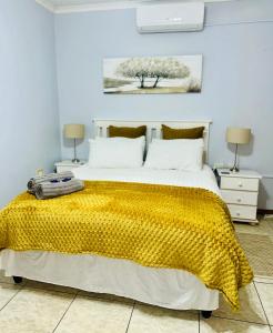 a bedroom with a large bed with a yellow blanket at O'Meara Overnight Rooms in Kimberley