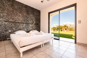 una camera da letto con un letto e una grande finestra di Villa Aigue Marine - Front de mer a Verghia Altre 24 foto