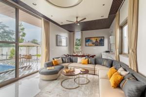a living room with a couch and a table at SaffronStays Raaga - luxury 4BR villa with private pool, lawns, gazebos & sweeping Aravalli hill views in Udaipur