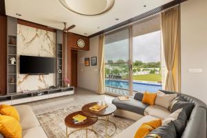 a living room with a couch and a tv at SaffronStays Raaga - luxury 4BR villa with private pool, lawns, gazebos & sweeping Aravalli hill views in Udaipur +47 photos