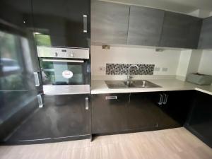 a kitchen with black cabinets and a sink at MK Getaways in Milton Keynes