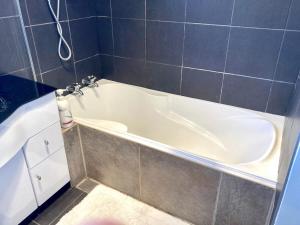 a white bath tub in a tiled bathroom at Oceans Edge Three-bed rooms spacious house in Bluff in Bluff +27 photos