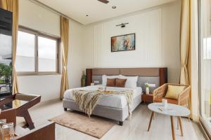 a bedroom with a bed and a table and a chair at SaffronStays Raaga - luxury 4BR villa with private pool, lawns, gazebos & sweeping Aravalli hill views in Udaipur