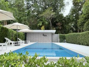 a swimming pool with two chairs and an umbrella at The Rinya Hotel Koh Phangan in Thong Sala