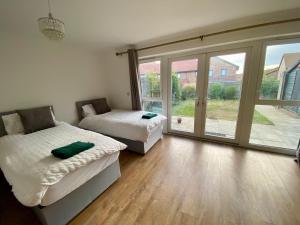 a bedroom with two beds and a large window at MK Getaways in Milton Keynes
