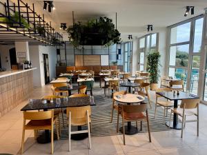 a restaurant with tables and chairs and windows at Mercure Rouen Val de Reuil in Val de Reuil