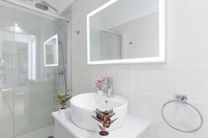 a white bathroom with a sink and a mirror at Superior Village Apartments - Porto Letizia in Porlezza