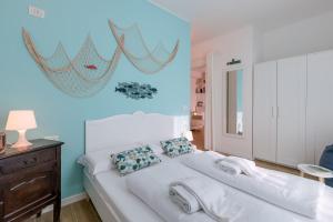 a bedroom with a white bed with blue walls at Superior Village Apartments - Porto Letizia in Porlezza