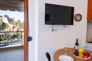 a kitchen with a table with a bowl of fruit and a tv on a wall at Venetian Studio in the Centre 1 in Heraklio