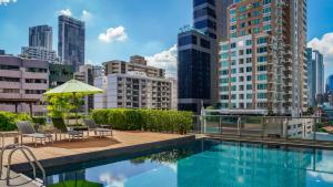 バンコクにあるOakwood Residence Sukhumvit 24 Bangkokの建物の上に椅子とパラソル付きのプールがあります。