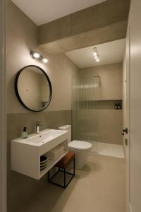 Un baño con lavabo, inodoro y espejo. en Rooftop Apt with Large Harbor View Terrace, en Constanţa
