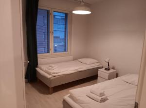 a small room with two beds and a window at Kotimaailma Apartments - kolmio Espoon keskuksessa in Espoo