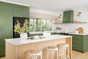 a kitchen with green cabinets and a counter with stools at Oak Ridge Cottage in Maleny +13 photos