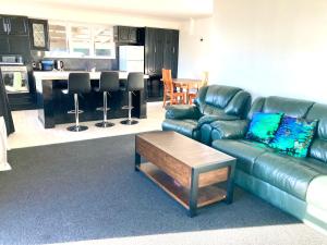 a living room with a leather couch and a table at Oceans Edge Three-bed rooms spacious house in Bluff in Bluff