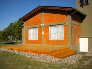 een huis met een houten terras naast een gebouw bij Las Casitas de Pepin in Santa Rosa de Calamuchita +3 foto's