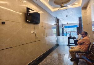 a man sitting in a chair in a lobby with a tv on the wall at Kaarthik Residency in Puducherry +21 photos