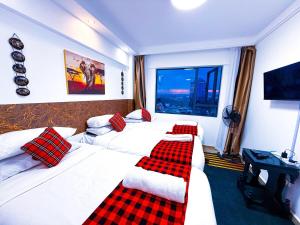 ein Hotelzimmer mit zwei Betten und rot-karierten Kissen in der Unterkunft 3BD Apartment - Pool, Gym, Children Play Area in Nairobi + 44 Fotos