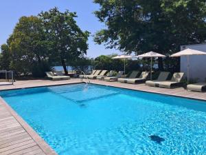 a large swimming pool with lounge chairs and umbrellas at Novotel Bordeaux Lac in Bordeaux