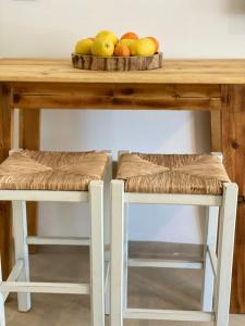 a table with a bowl of fruit and two stools at צימר על הנחל in Metsudat Menahem Ussishkin Alef