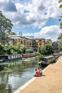 a child sitting on a sidewalk next to a river at Deluxe Studio Flat - King's Cross - by KeyHol Holiday Let in London