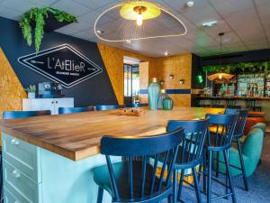 un restaurant avec un grand bar en bois avec des chaises bleues dans l'établissement Novotel Mulhouse Bâle Fribourg, à Sausheim