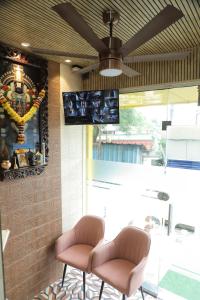 2 sillas en una habitación con TV en la pared en HOTEL IRIS inn, en Dombivli