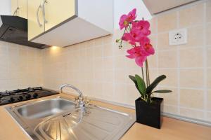 eine Küche mit einer Spüle und einer Vase mit rosa Blumen in der Unterkunft Apartments Pako in Pakoštane + 187 Fotos