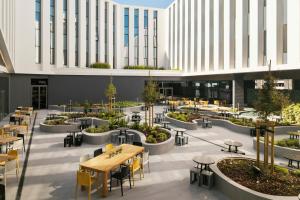 a cafeteria with tables and chairs in a building at Moxy Alfragide Lisboa in Alfragide