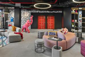 a living room with a pink couch and chairs at Moxy Alfragide Lisboa in Alfragide +59 photos