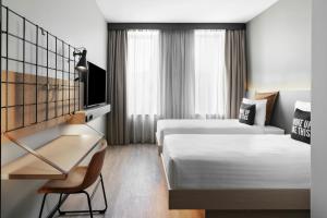 a hotel room with two beds and a desk at Moxy Alfragide Lisboa in Alfragide +71 photos