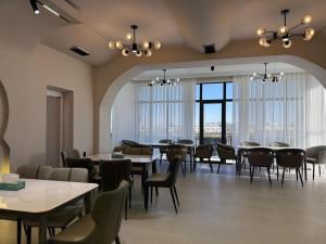 Un comedor con mesas y sillas y ventanas. en Turkezm Hotel, en Urganch