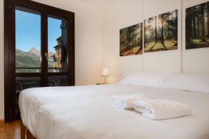 una camera da letto con un letto bianco con due asciugamani sopra di El mirador de Panticosa l WIFI l Garaje l Vistas a Panticosa