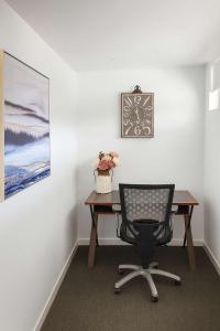 a desk with a chair and a clock on a wall at Home to Holiday at Central Islington Apartments in Townsville +11 photos