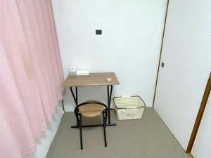 ein kleiner Tisch mit einem Stuhl neben einem rosa Vorhang in der Unterkunft ゲストハウスひわまり セルフチェックイン 瓦町すぐ in Takamatsu + 54 Fotos