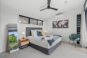a bedroom with a bed and a ceiling fan at Boutique Coastal Retreat with Bath Walk to Beach in Mangawhai