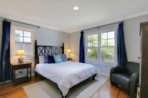 a bedroom with a bed and a chair and two windows at Little Palm Cottage in Santa Barbara +32 photos