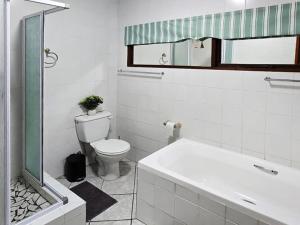 a bathroom with a toilet and a sink and a tub at In Vrede in George