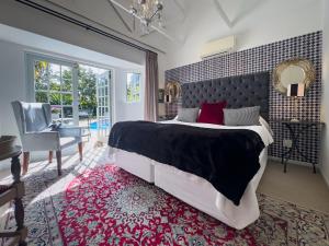 a bedroom with a large bed and a chair at Baruch Guesthouse on Lovell in Stellenbosch
