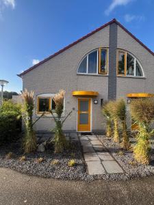 a house with a yellow door and some plants at Kustverhuur, Vakantiepark Fort Soleil 24 in Breskens