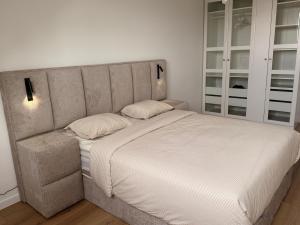 une chambre avec un grand lit avec des draps blancs dans l'établissement Skyline WIFI Parking - Confort, à Bruxelles
